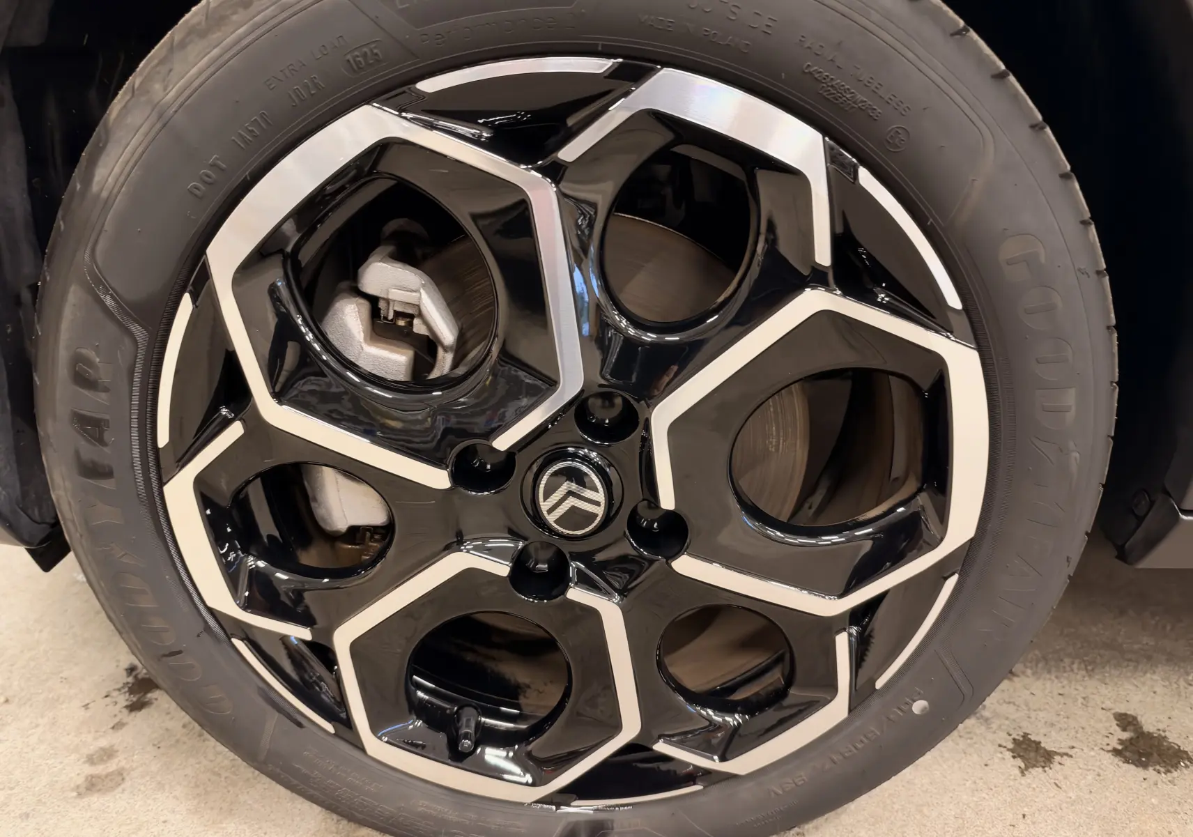 Gros plan sur la jante noire et argentée d’une Citroën E-C3 gris 2025, mettant en valeur le logo central et le pneu Goodyear.