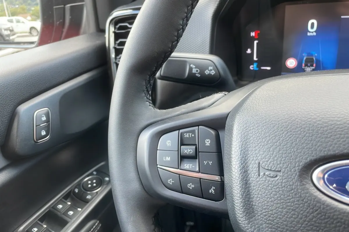 Gros plan sur le volant noir du Ford Ranger 2025 avec commandes intégrées et tableau de bord numérique visible.