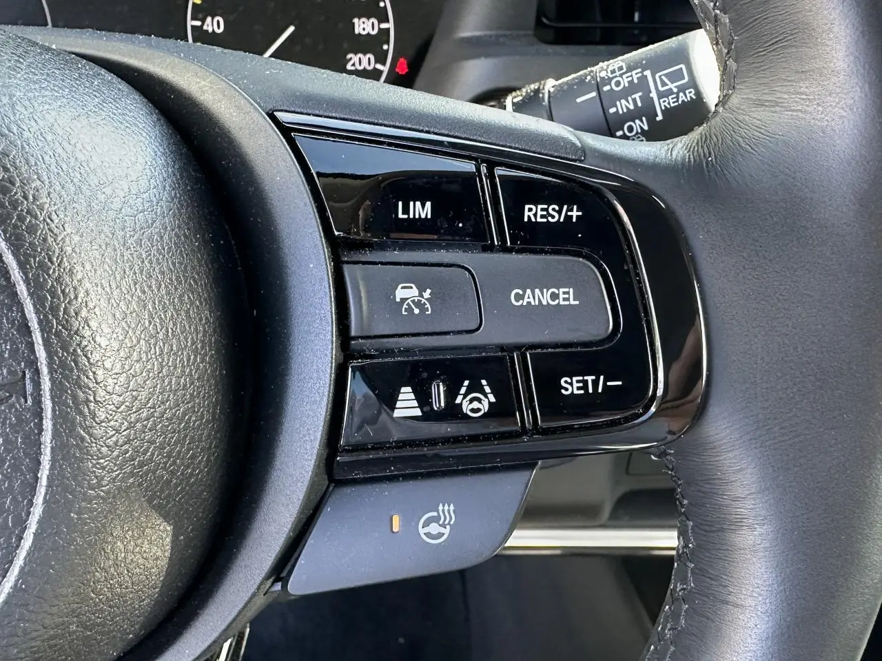 Gros plan sur les commandes du volant cuir noir du Honda HR-V 2025, avec régulateur de vitesse et volant chauffant.