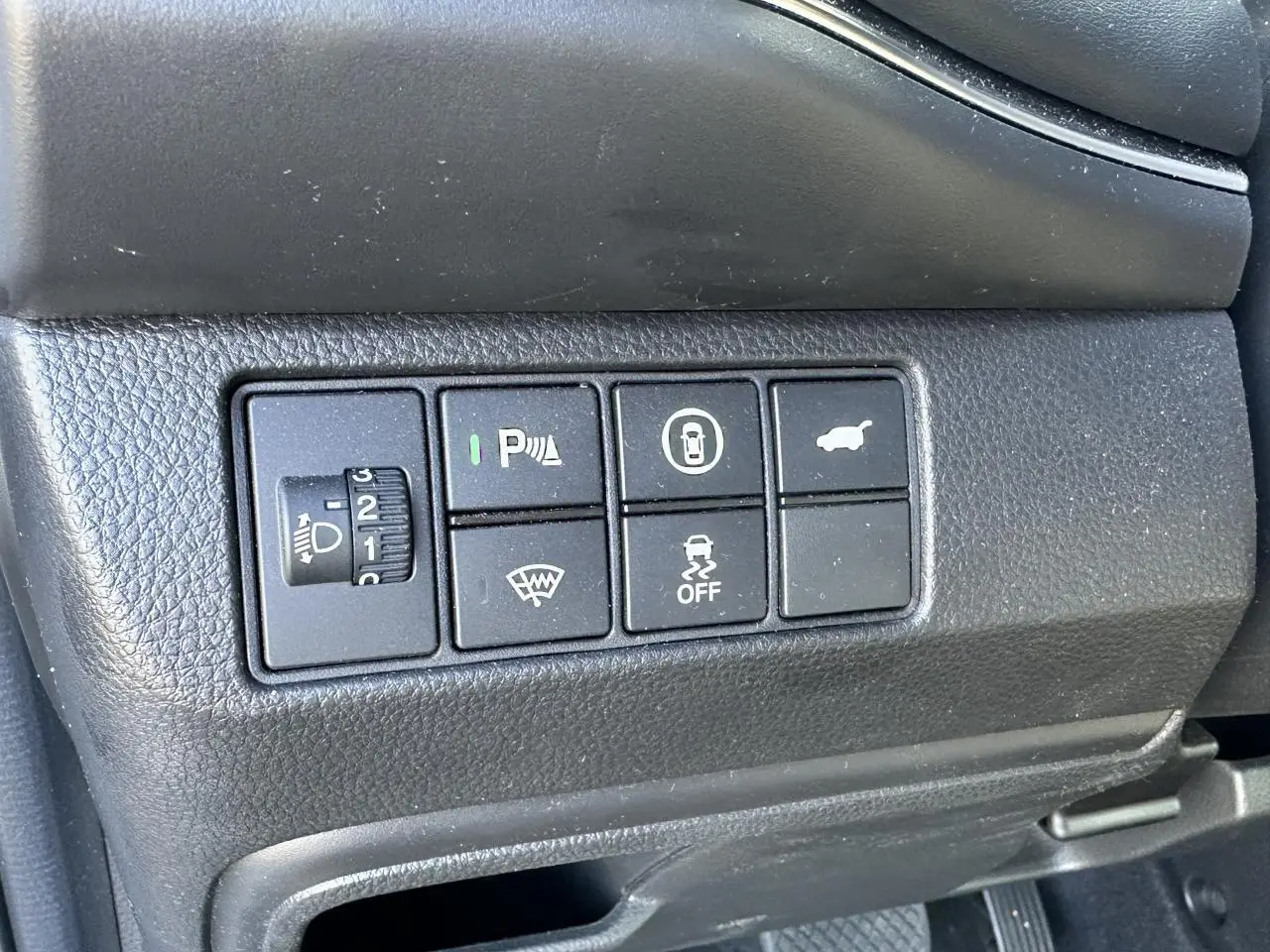 Gros plan sur les commandes de fonctions électroniques côté gauche du tableau de bord noir du Honda HR-V gris 2025.
