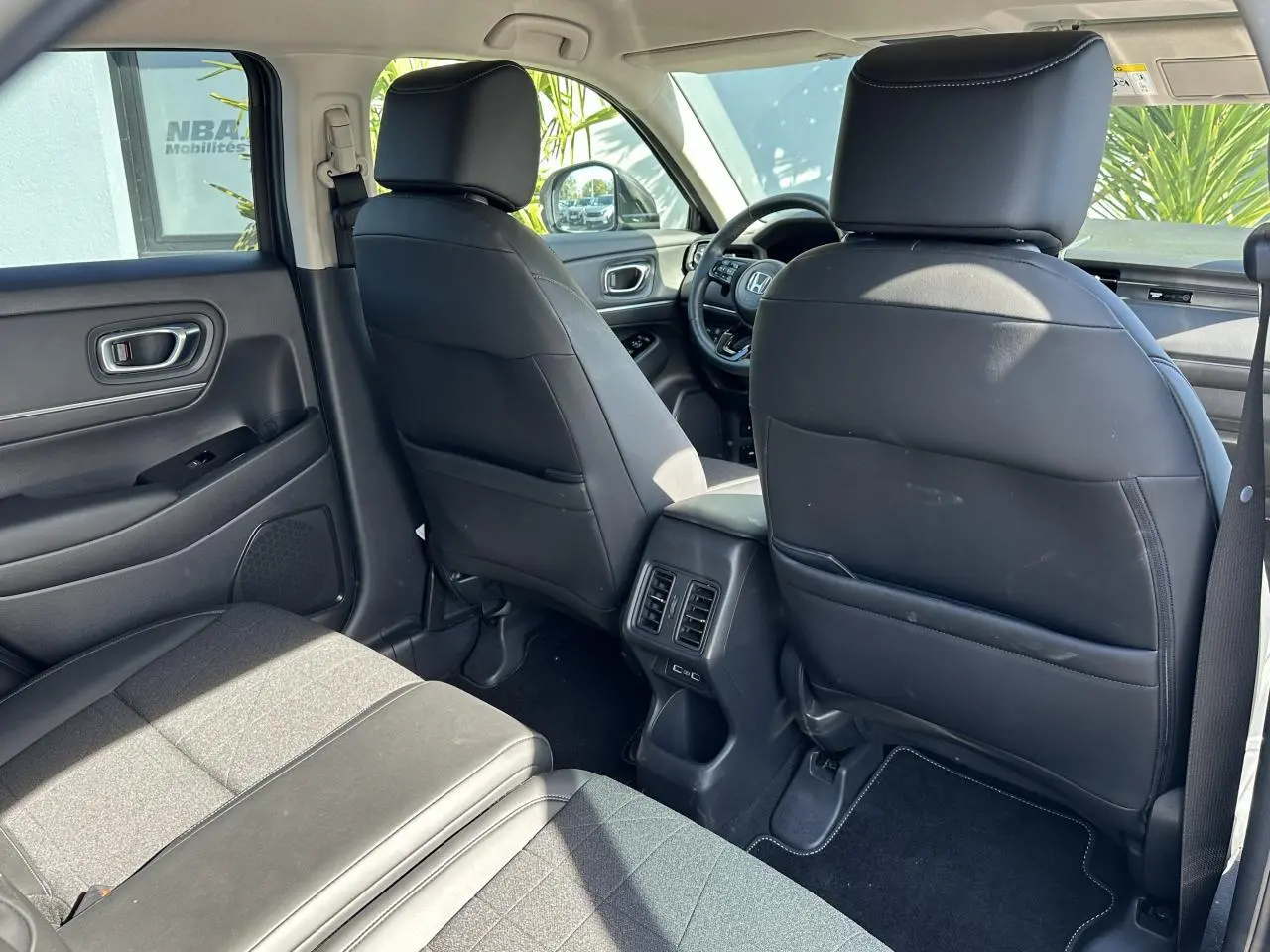 Vue intérieure arrière du Honda HR-V 2025 avec sièges noirs en cuir synthétique et tissu, et prises USB arrière visibles.