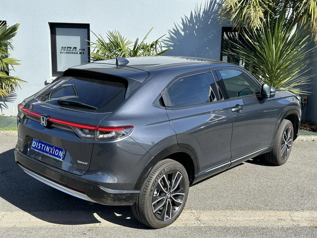 Honda HR-V gris métallisé vu en 3/4 arrière côté droit, avec feux arrière LED et jantes alliage 18 pouces.