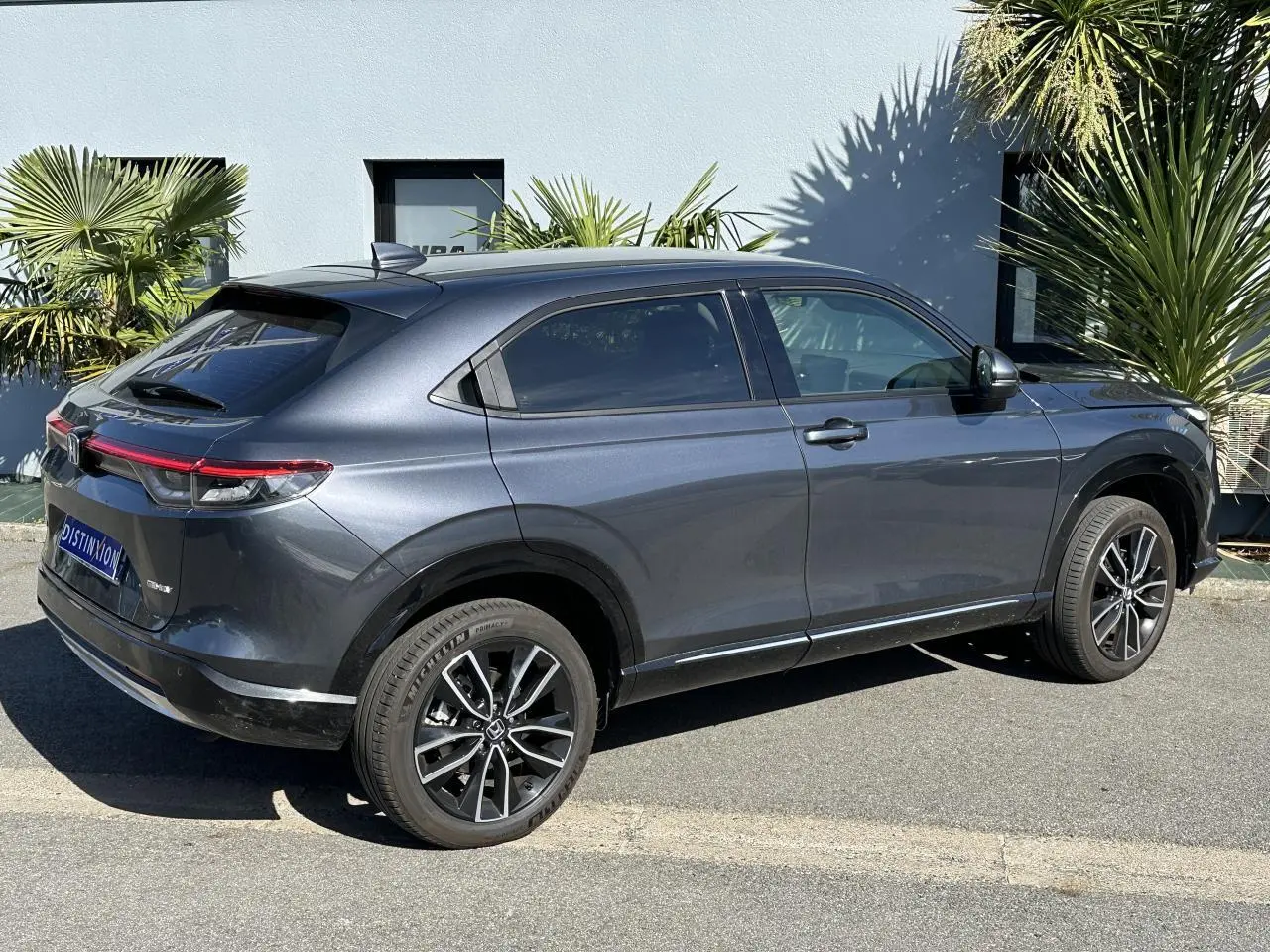 Vue 3/4 arrière droite d'un Honda HR-V gris métallisé 2025 avec jantes alliage et feux arrière LED connectés.