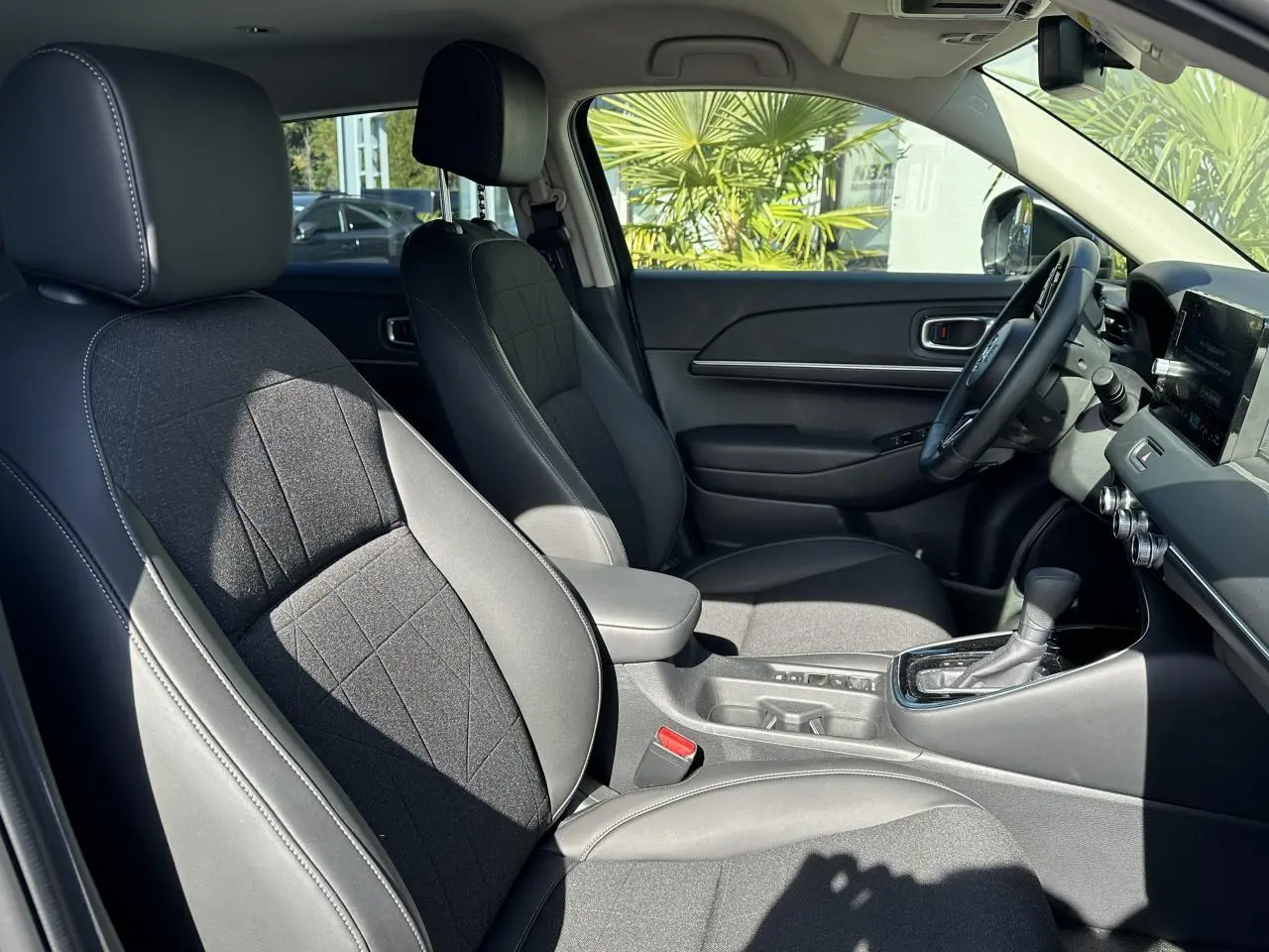 Intérieur avant du Honda HR-V 2025, sièges cuir synthétique et tissu noirs, console centrale avec levier de boîte automatique.