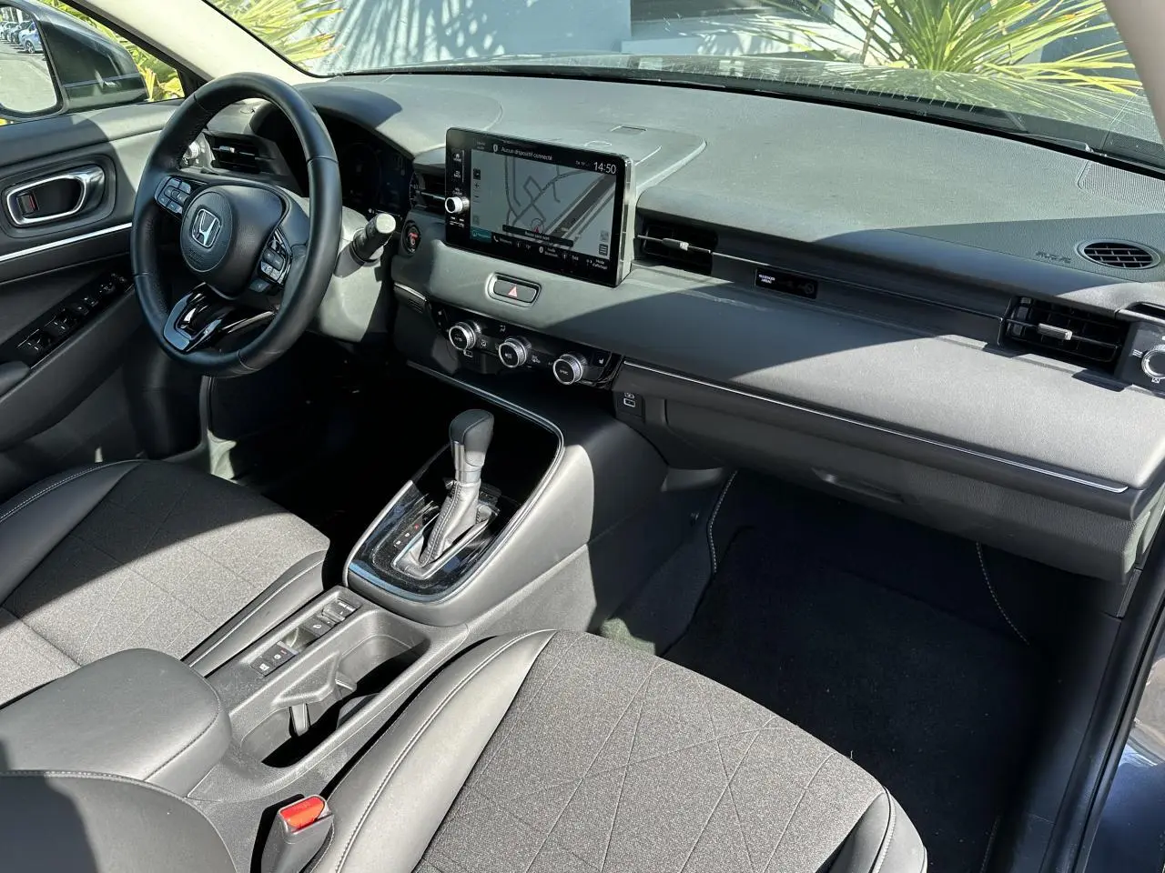 Intérieur avant droit du Honda HR-V gris 2025 avec tableau de bord moderne, écran tactile et sièges en cuir synthétique.