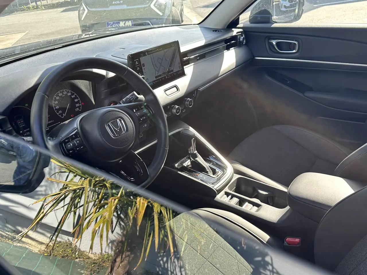 Intérieur du Honda HR-V 2025 vu côté conducteur, volant cuir, écran tactile central et sièges noirs en tissu et cuir.