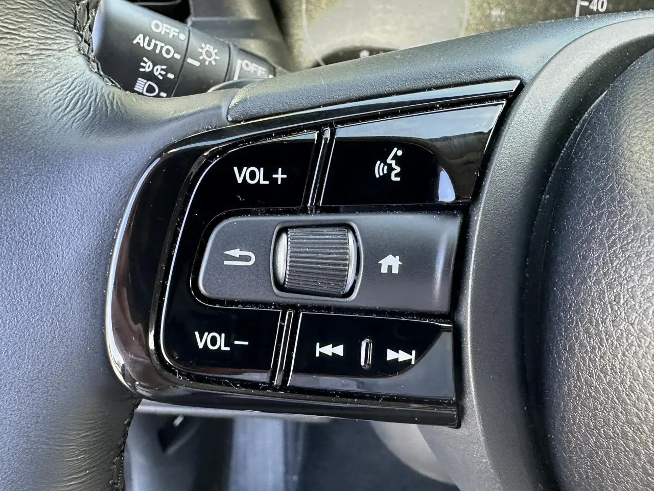 Gros plan sur les commandes audio au volant cuir noir du Honda HR-V 2025 gris hybride essence.