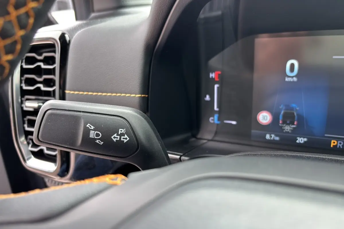 Détail du commodo de clignotant et tableau de bord numérique du Ford Ranger 2025 noir agate avec surpiqûres orange.