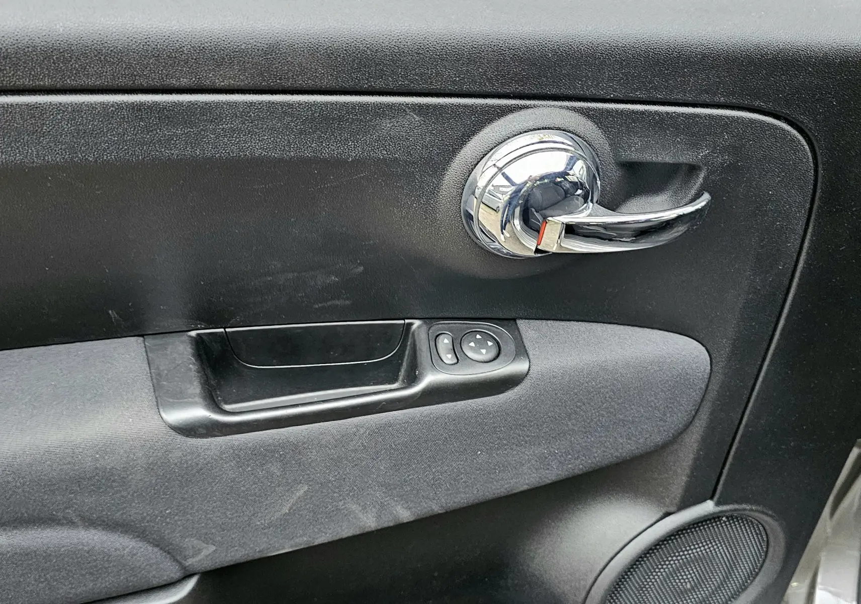 Poignée de porte intérieure chromée côté droit de la FIAT 500 gris 2023 avec commandes électriques des rétroviseurs.