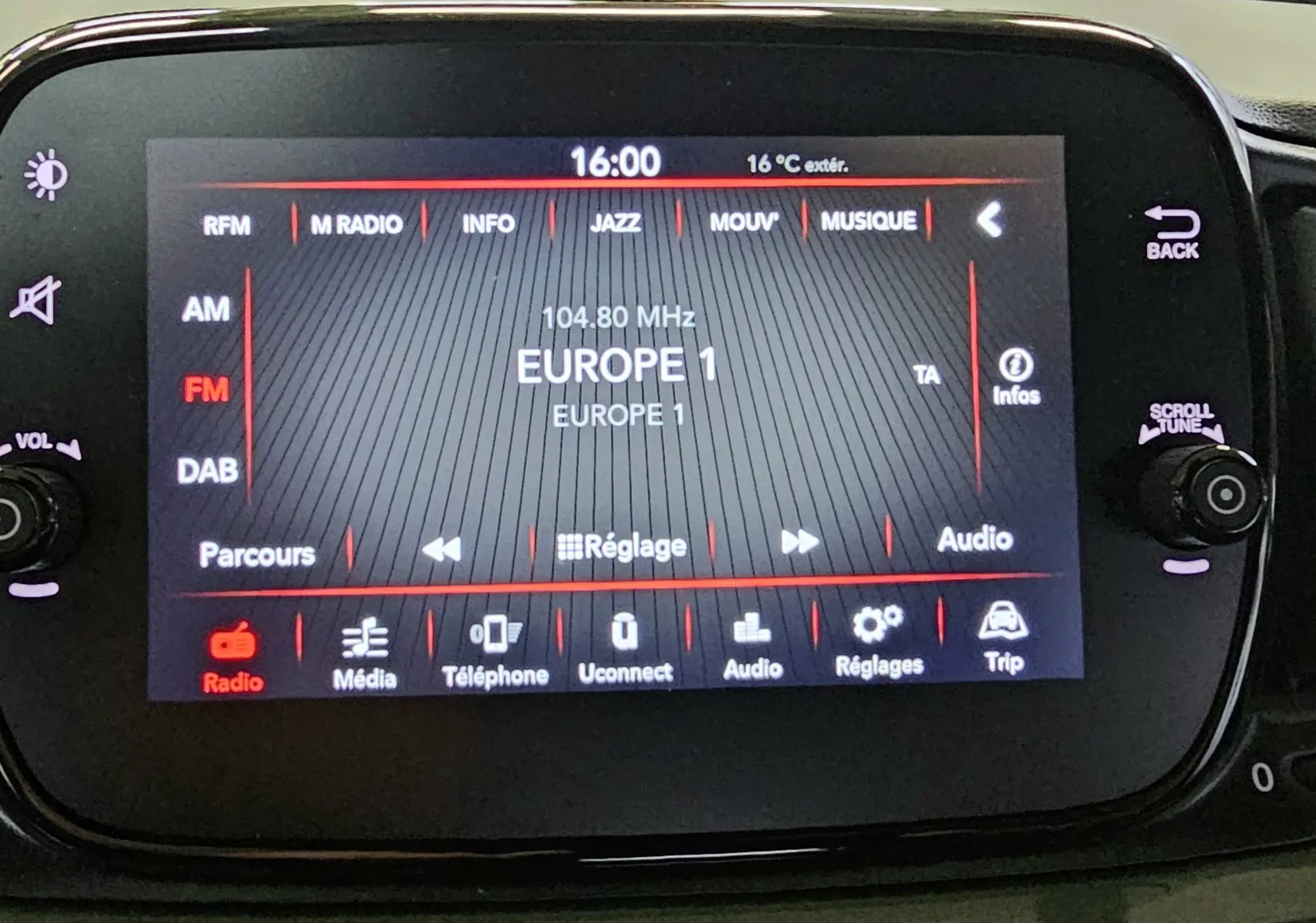 Écran tactile central de la FIAT 500 gris 2023 affichant la radio FM Europe 1 à 16h00 avec commandes autour.