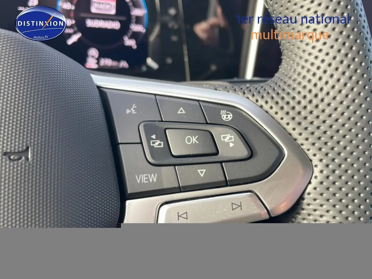 Gros plan sur les commandes multifonctions en cuir perforé du volant côté gauche d'une Volkswagen Golf gris 2026.