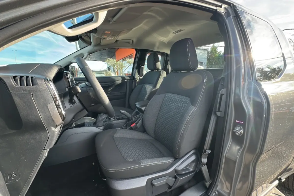 Vue intérieure côté conducteur du Ford Ranger gris iconic 2025, montrant les sièges avant et le volant multifonctions cuir.