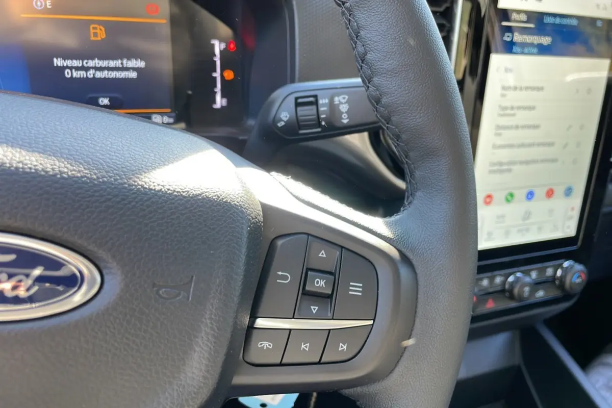 Gros plan sur le volant cuir multifonctions côté droit du Ford Ranger 2025 avec écran tactile et commandes au volant visibles.