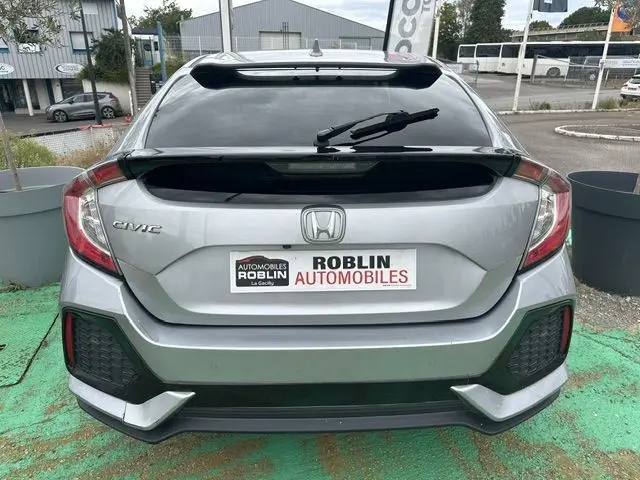 Vue arrière d'une Honda Civic grise 5 portes de 2019, avec lunette arrière teintée et essuie-glace central.