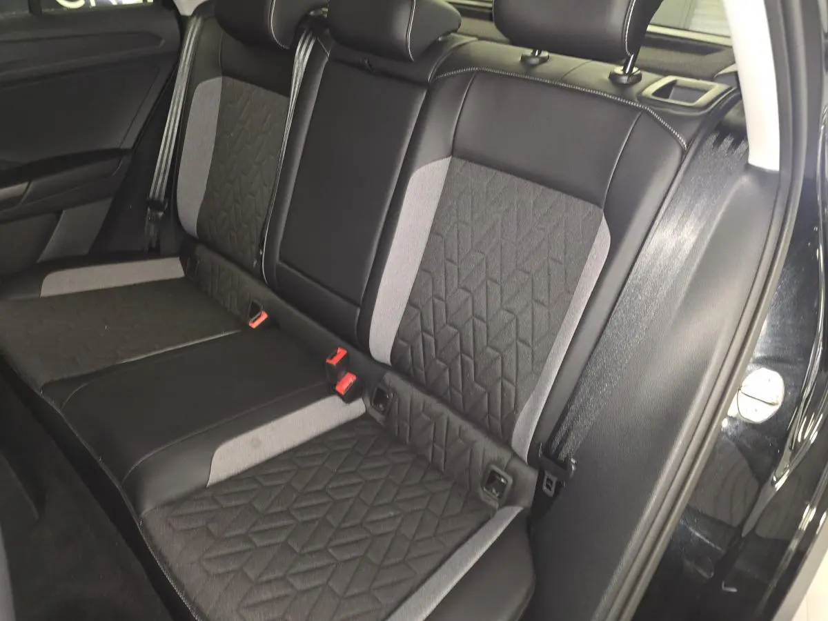 Vue latérale de la banquette arrière en tissu noir et gris du Volkswagen T-Roc noir 2025, avec ceintures de sécurité visibles.