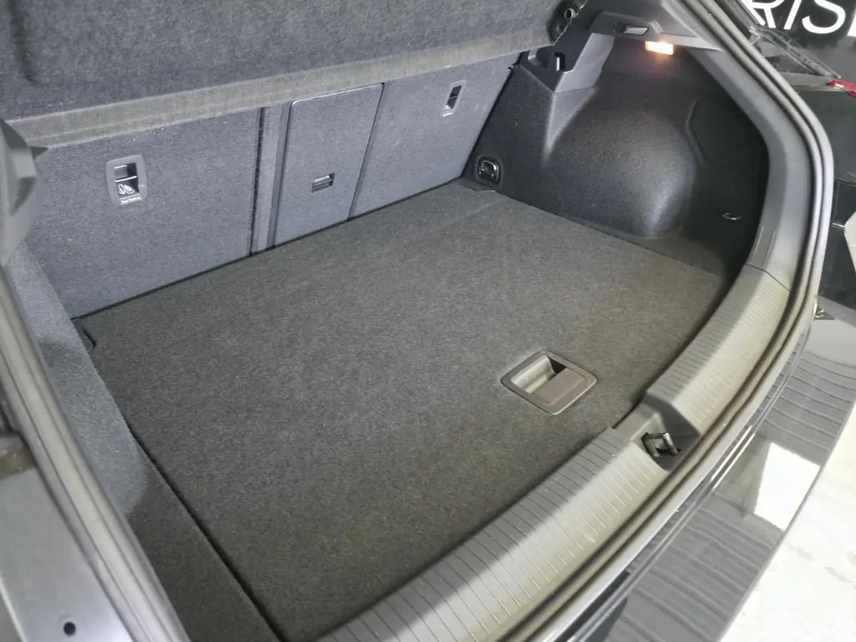 Coffre ouvert du Volkswagen T-Roc noir, vue intérieure montrant le plancher plat et les sièges arrière rabattables.