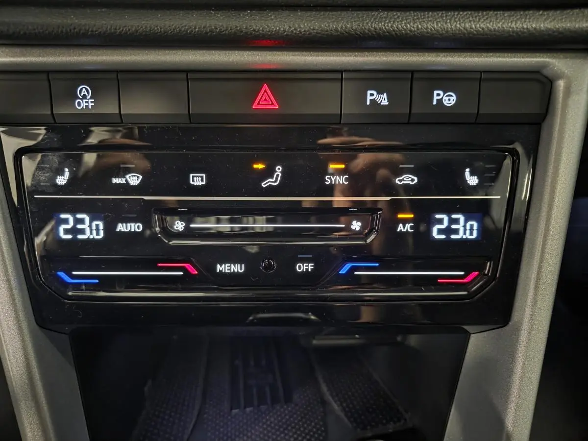Gros plan sur la console centrale du Volkswagen T-Roc 2025 montrant la climatisation automatique bi-zone réglée à 23°C.