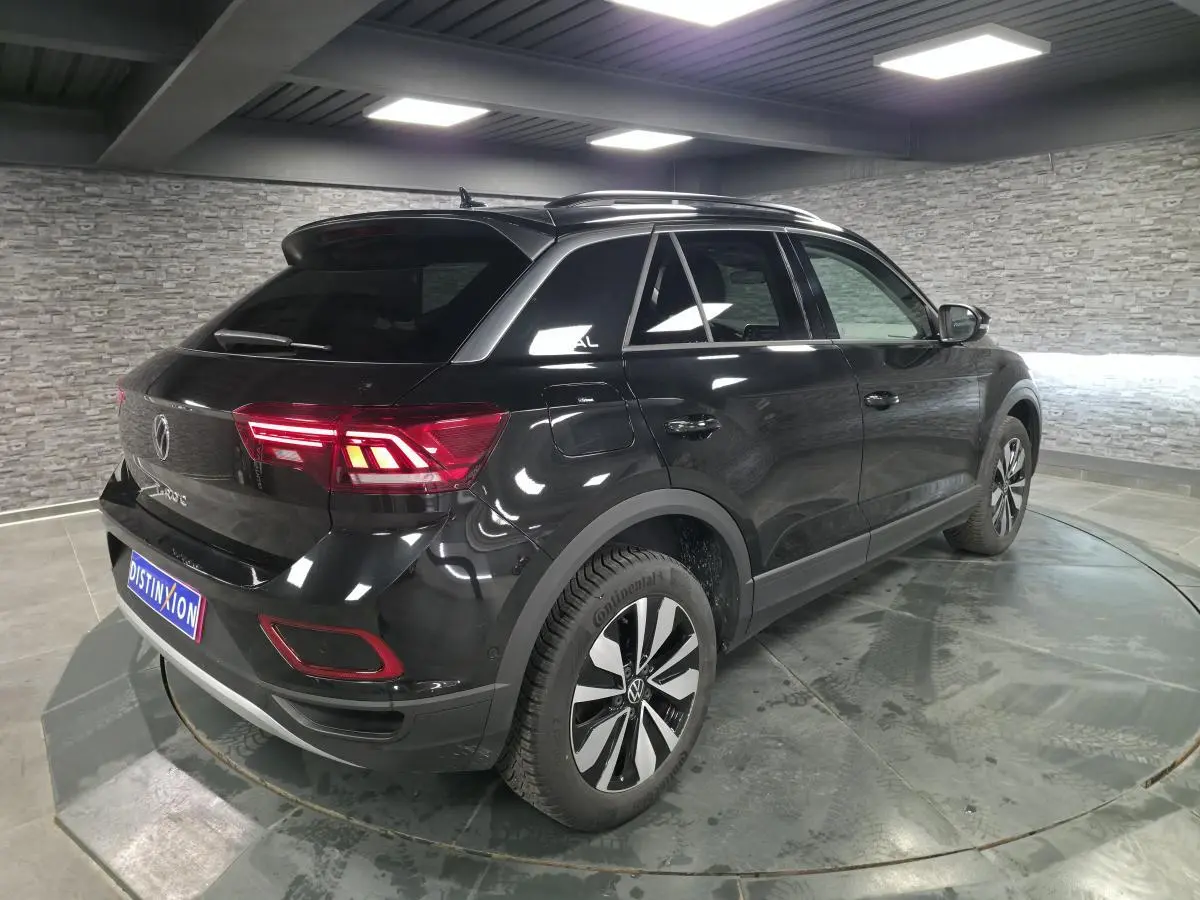 Vue 3/4 arrière droite du Volkswagen T-Roc noir nacré avec jantes alliage 17 pouces et feux arrière LED allumés.