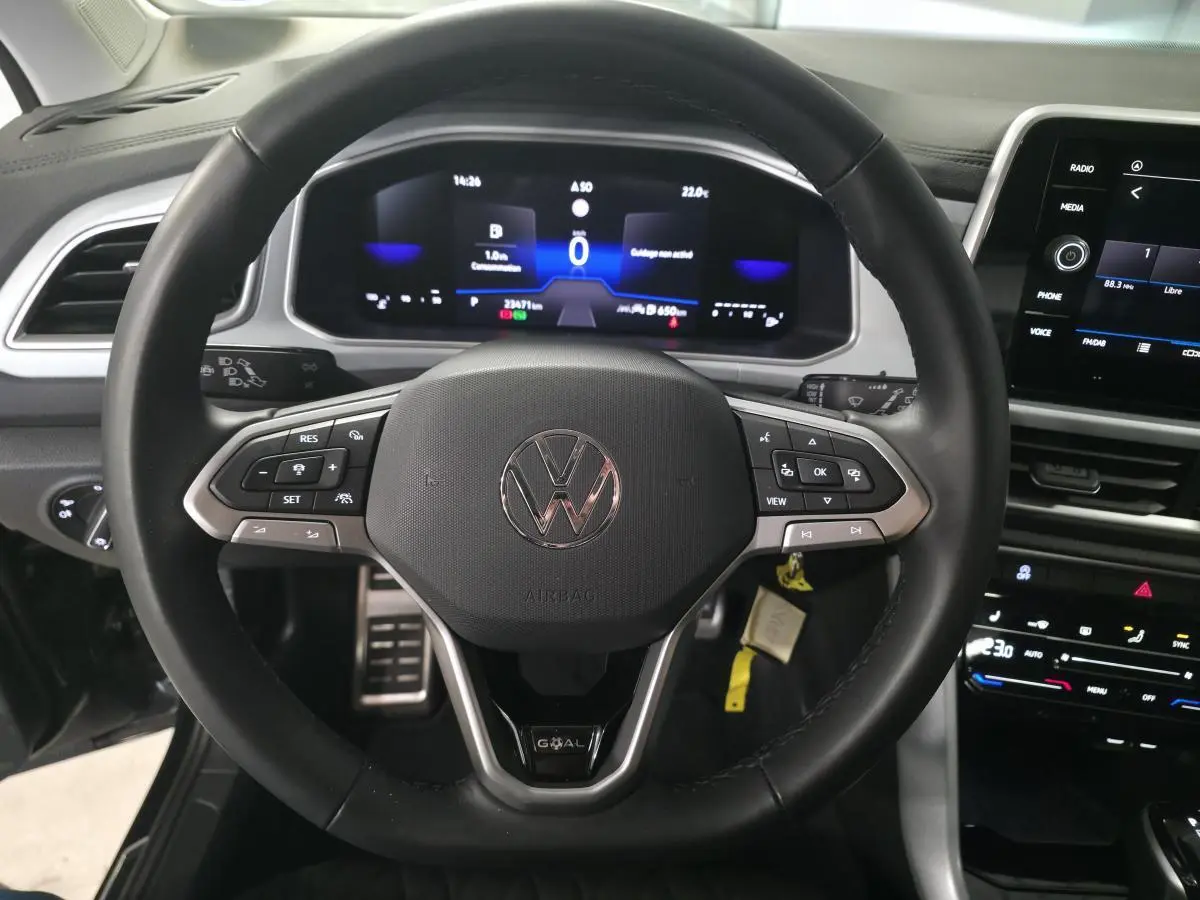 Volant noir multifonction Volkswagen T-Roc 2025 avec tableau de bord digital et écran tactile central visible de face.