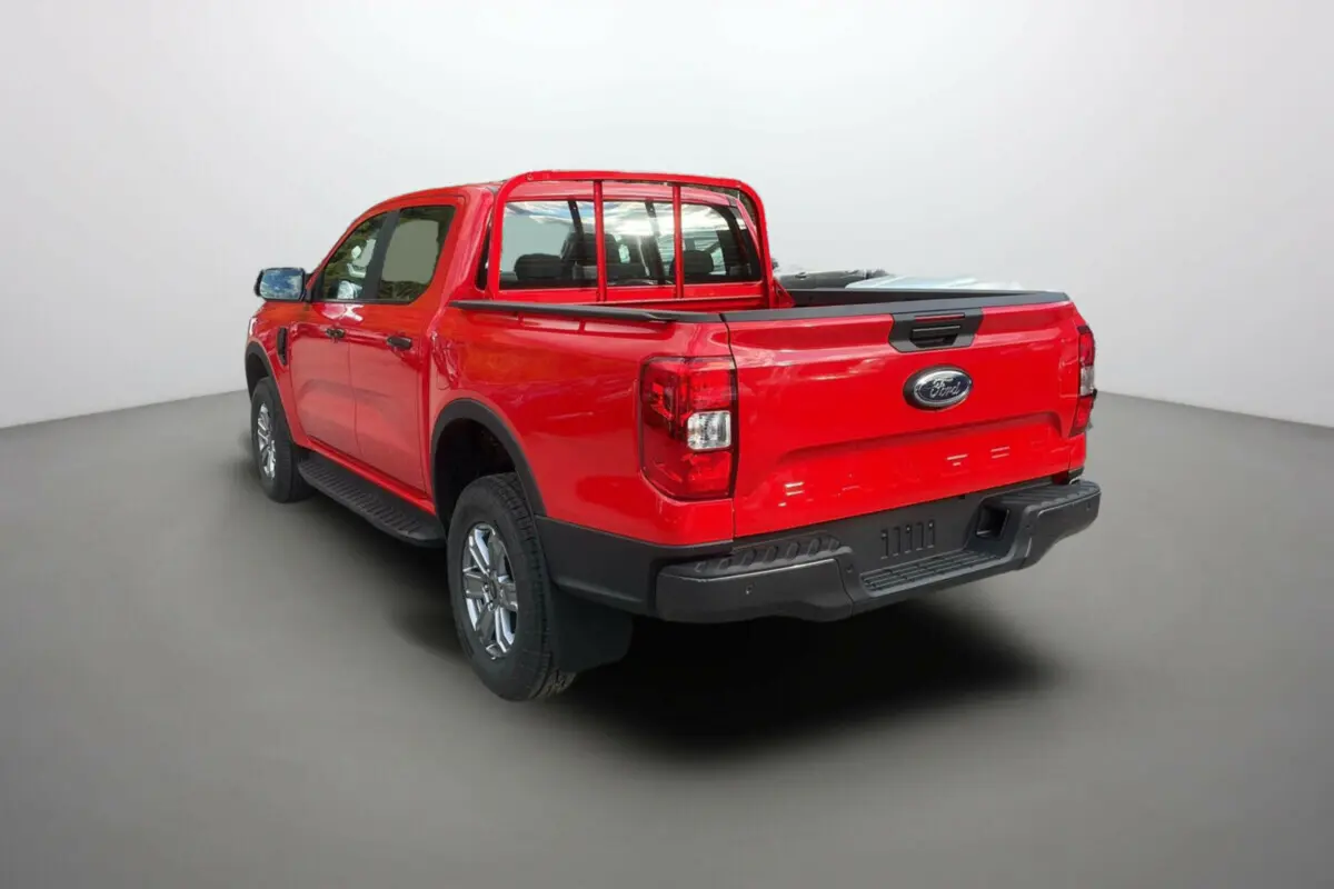 Ford Ranger rouge racing en 3/4 arrière droit, avec benne et protection de cabine visibles dans un studio lumineux.