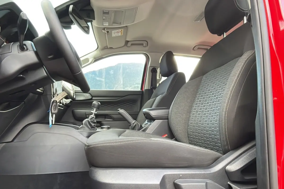 Intérieur du Ford Ranger 2025 rouge racing, vue côté conducteur montrant sièges noirs et levier de vitesses manuel.
