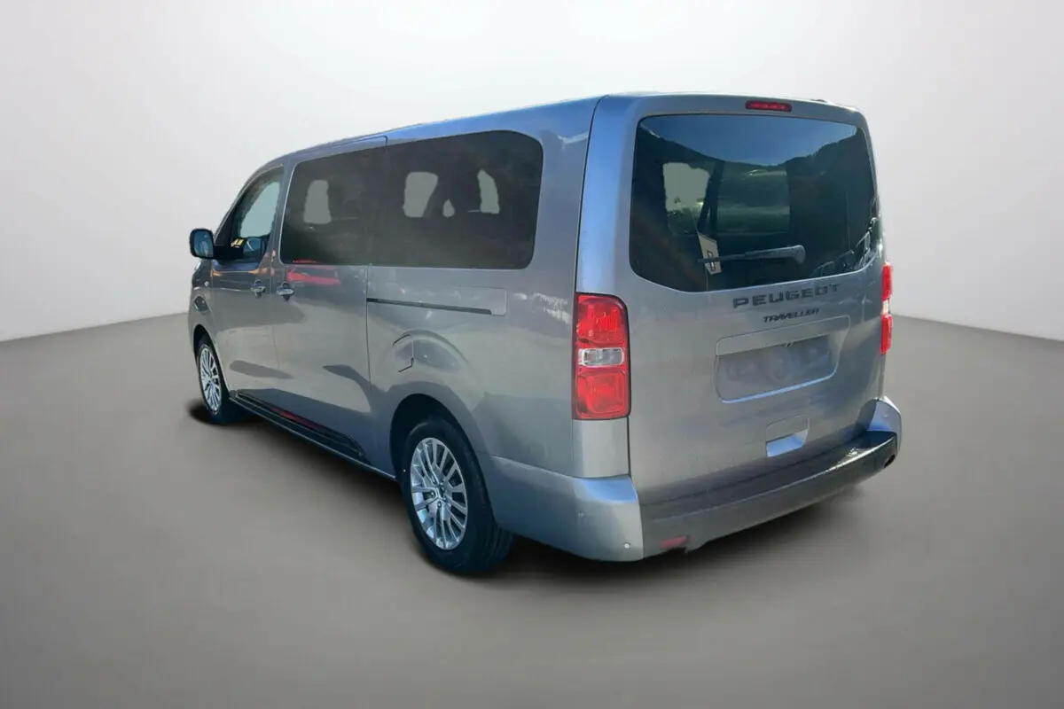 Vue 3/4 arrière droite d'un Peugeot Traveller gris acier avec vitres surteintées et deux portes coulissantes.