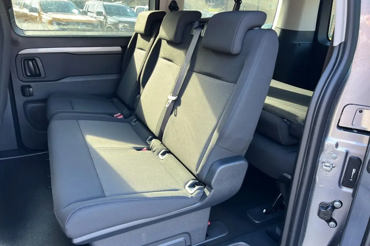 Vue intérieure côté droit sur la banquette arrière grise du Peugeot Traveller 2025 avec porte coulissante ouverte.