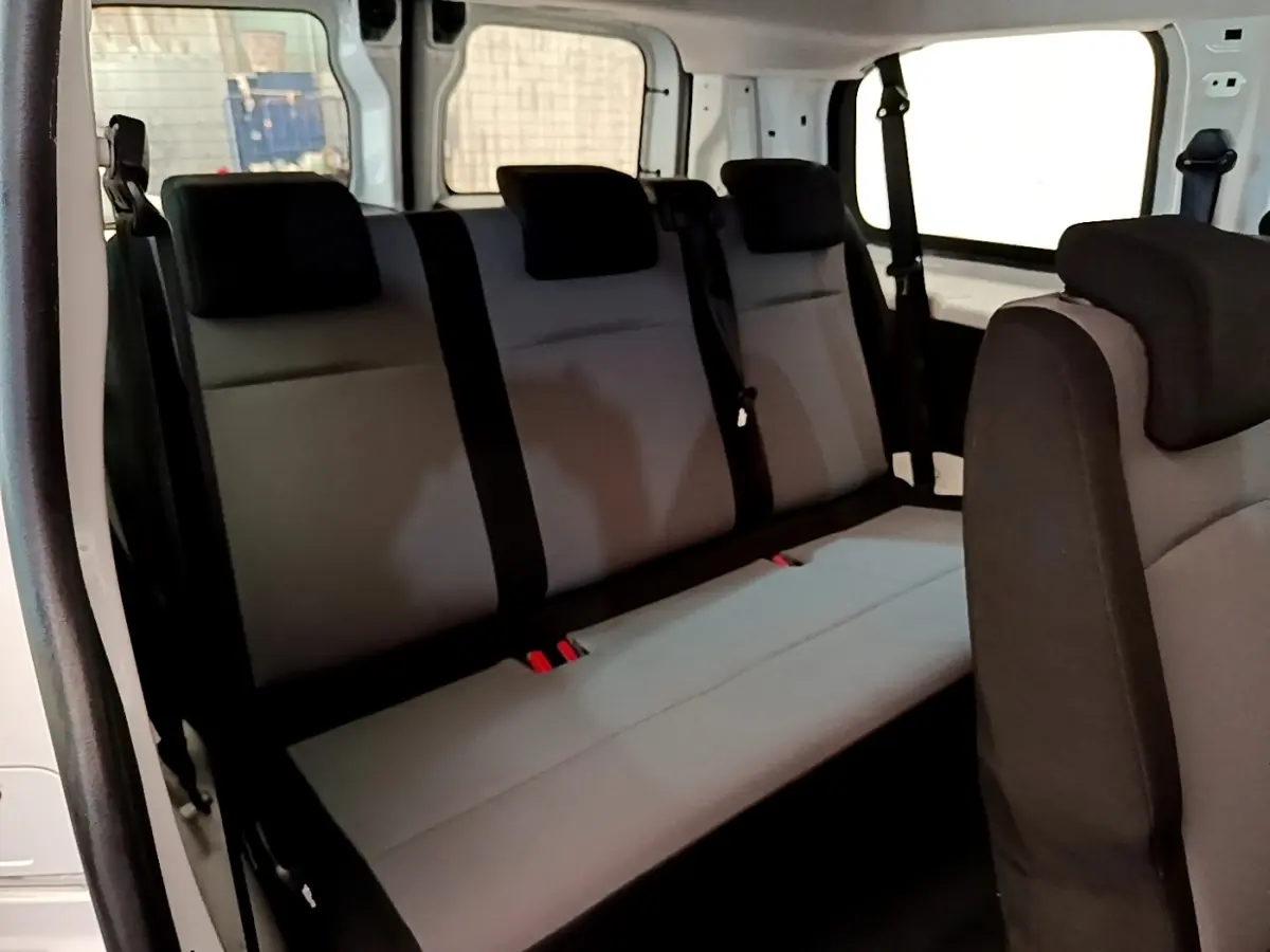 Vue intérieure côté gauche du Peugeot Traveller 2018 blanc, montrant la banquette arrière grise avec appuie-têtes noirs.