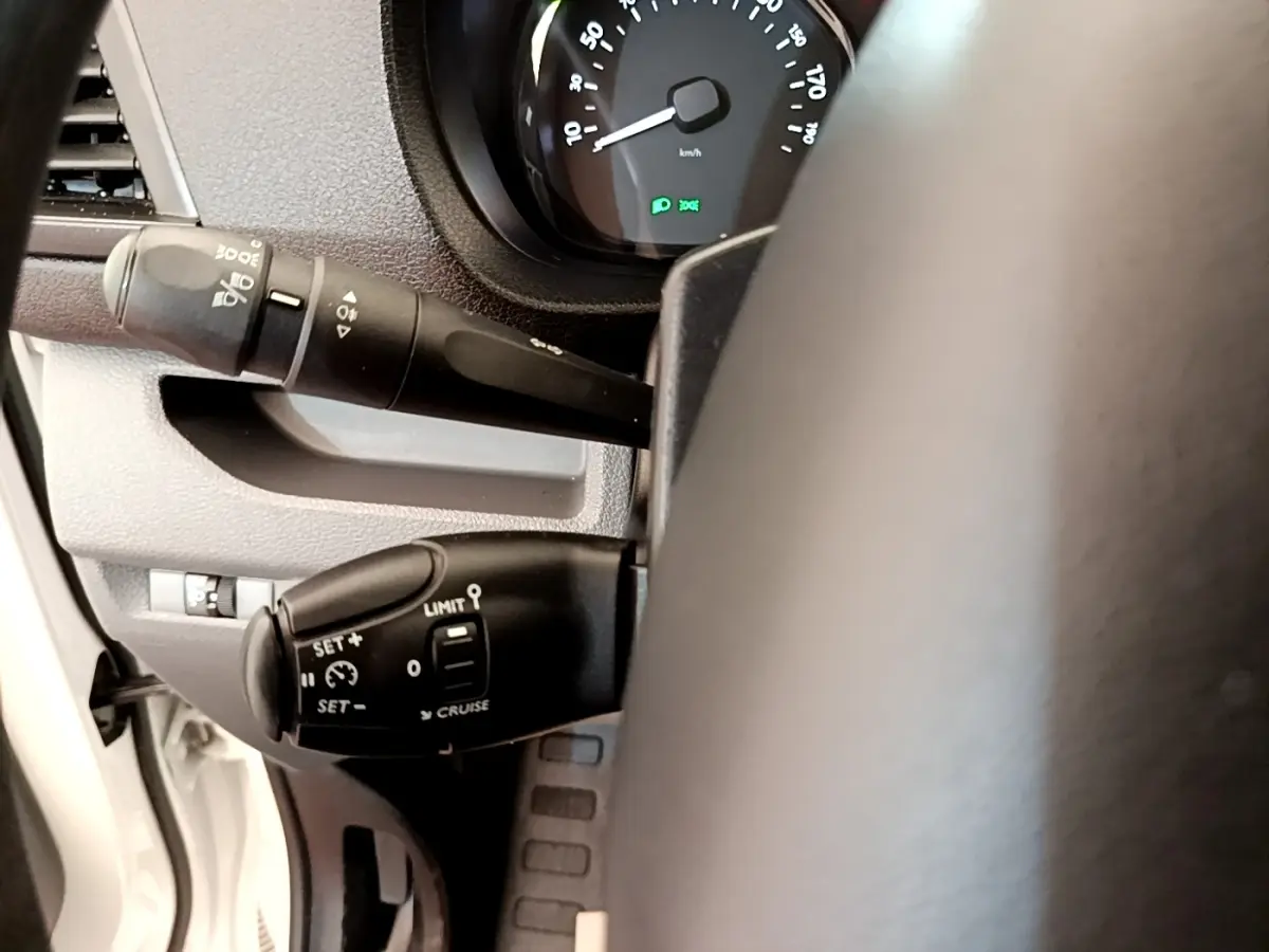 Gros plan sur la commande de régulateur de vitesse et clignotants du Peugeot Traveller blanc, vue côté gauche du volant.
