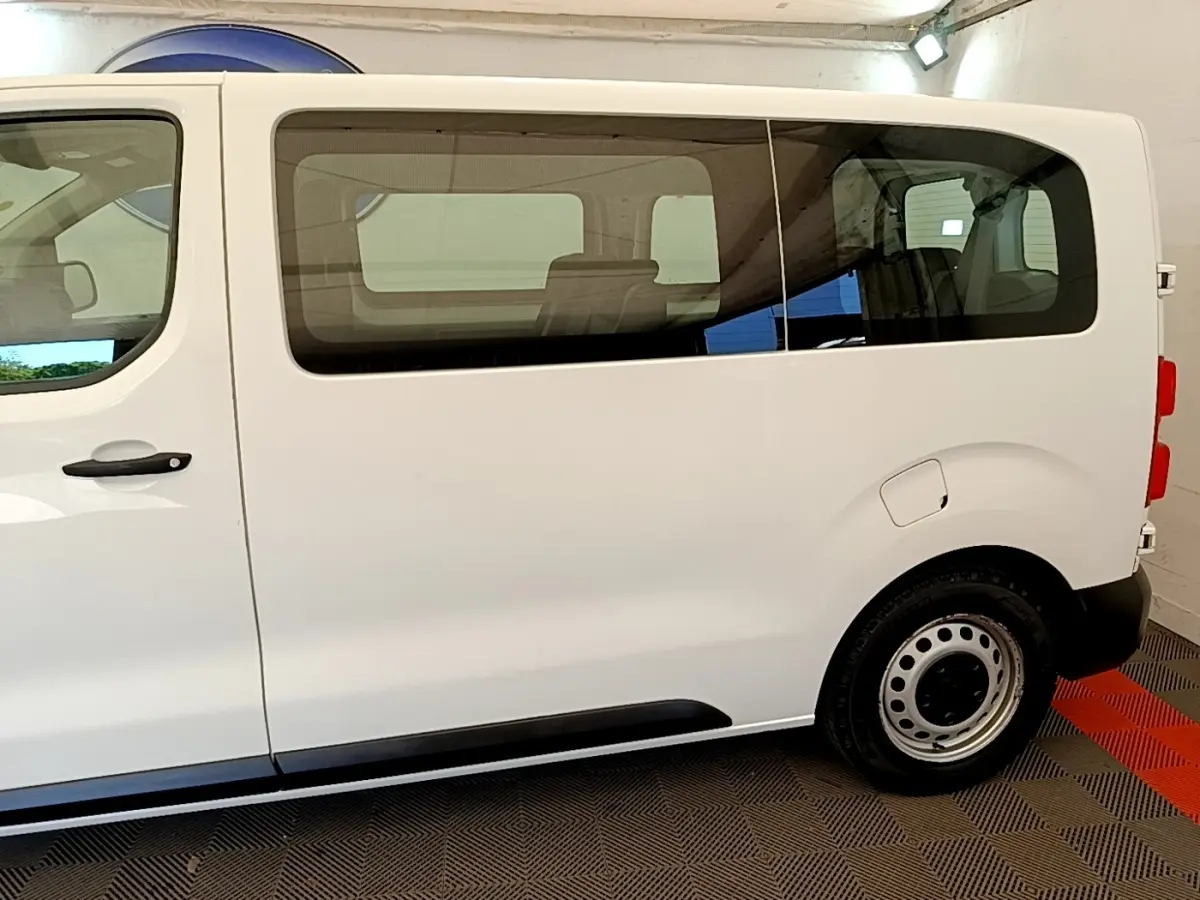 Vue de profil côté droit d’un Peugeot Traveller blanc 2018 avec vitres teintées et jantes acier.