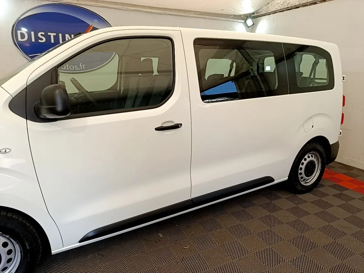 Vue de profil côté gauche d’un Peugeot Traveller blanc 2018 avec vitres teintées et jantes acier noires.