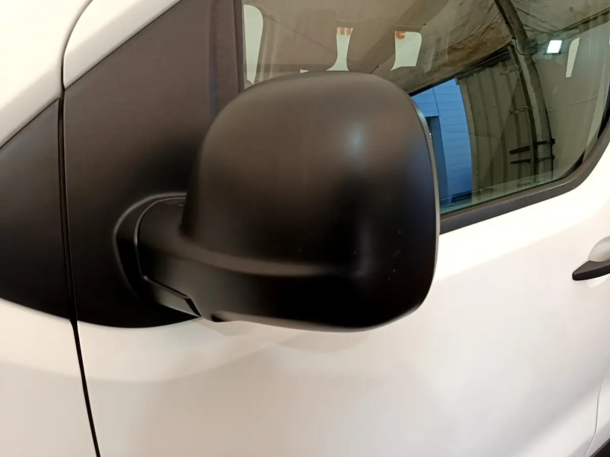 Rétroviseur noir en gros plan côté gauche d’un Peugeot Traveller blanc de 2018, avec porte et vitre visibles.