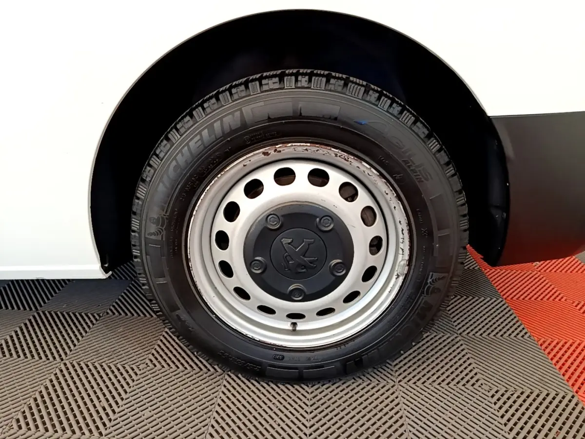 Gros plan sur la roue avant droite d’un Peugeot Traveller blanc de 2018 avec jante acier et pneu Michelin.