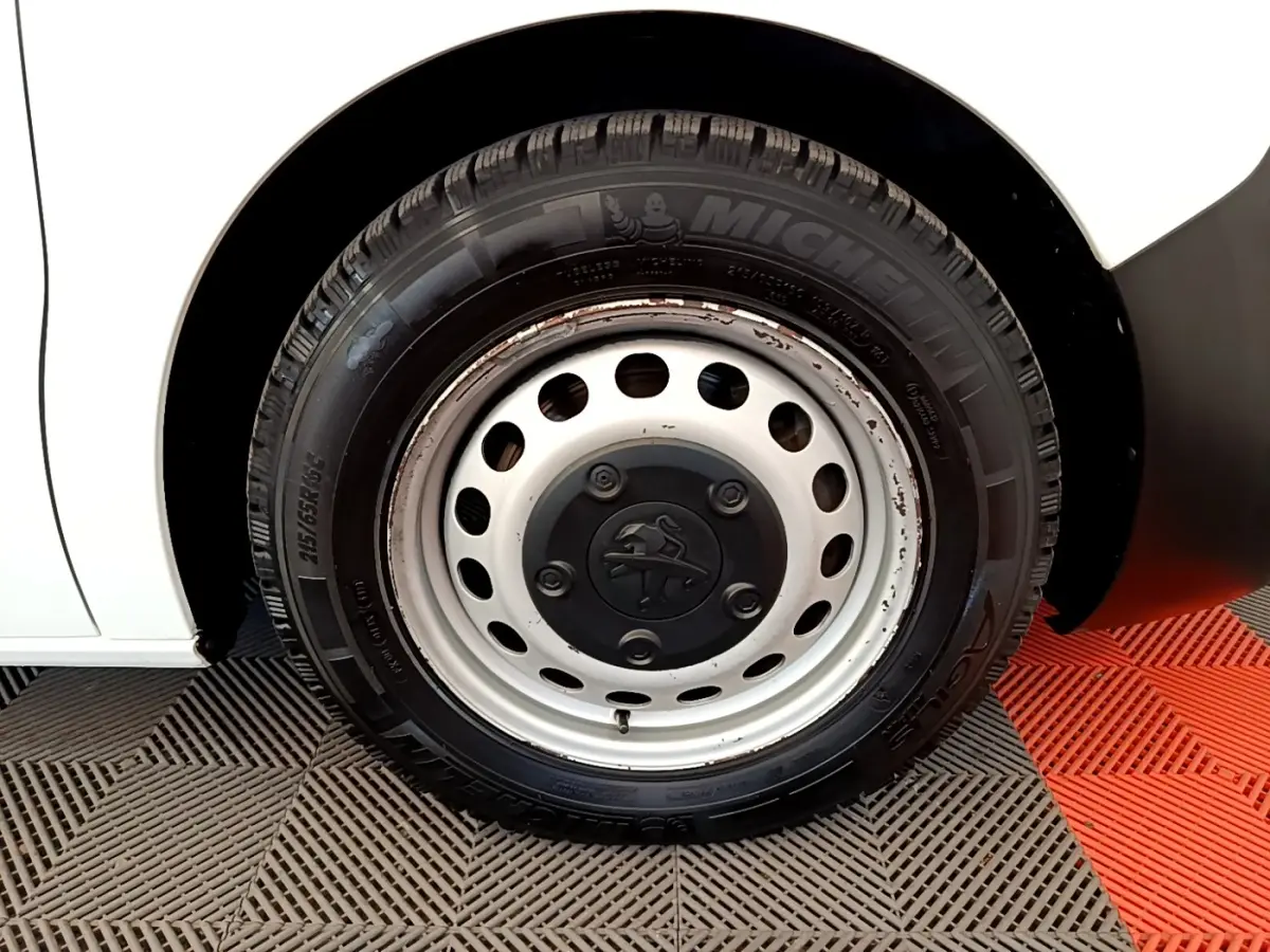 Gros plan sur la roue avant gauche blanche d’un Peugeot Traveller 2018 avec jante acier et pneu Michelin.