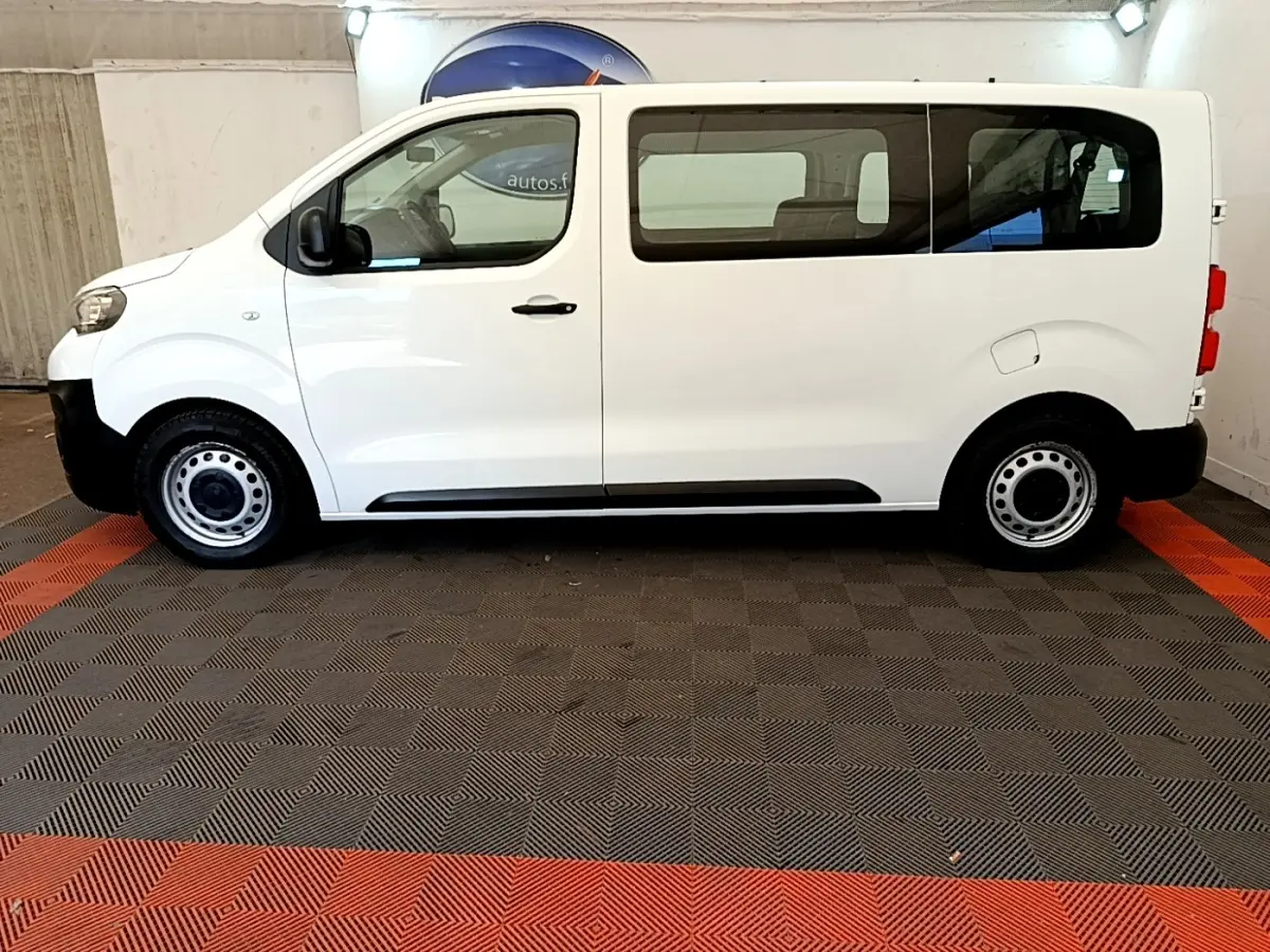 Vue de profil côté gauche d'un Peugeot Traveller blanc de 2018 avec jantes acier et vitres teintées arrière.