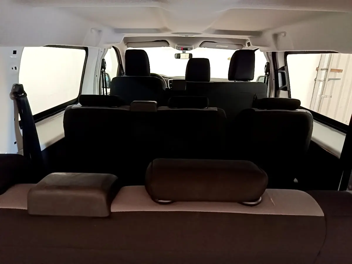 Vue intérieure arrière du Peugeot Traveller blanc 2018, montrant les sièges noirs et l'habitacle spacieux.