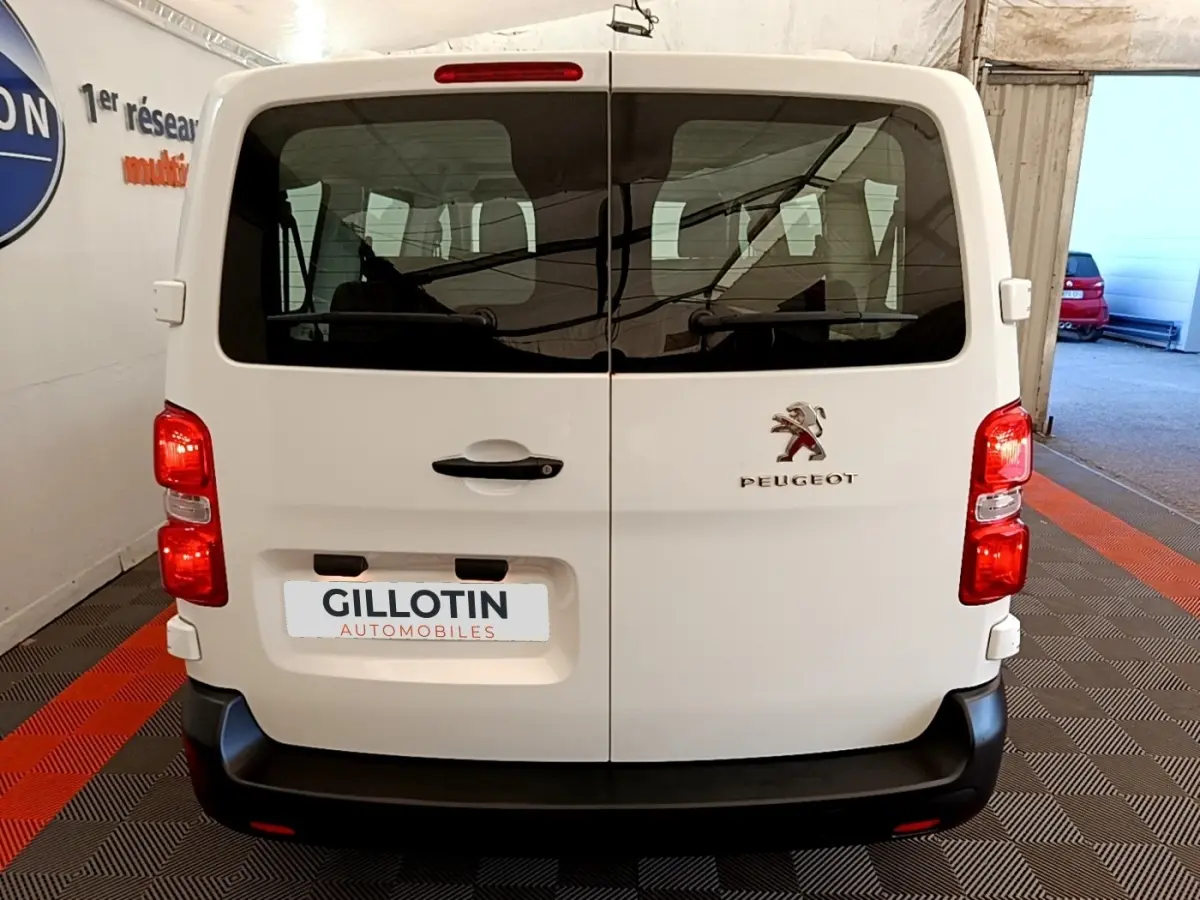 Vue arrière d’un Peugeot Traveller blanc de 2018 avec portes battantes et feux rouges allumés en intérieur.