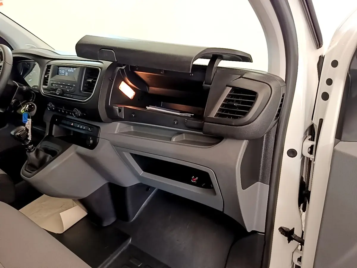 Intérieur du Peugeot Traveller blanc 2018, vue côté passager avec boîte à gants ouverte et tableau de bord visible.