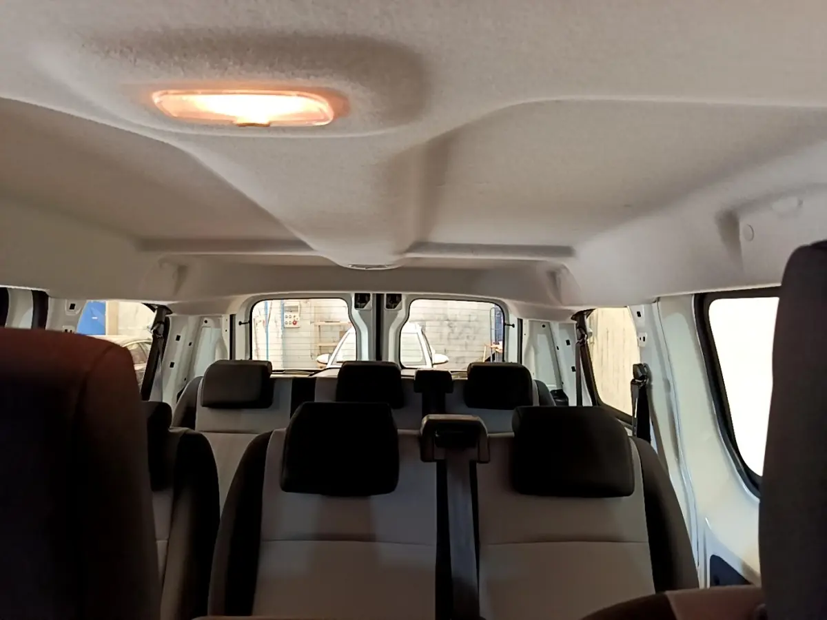 Vue intérieure arrière du Peugeot Traveller blanc 2018 montrant les sièges passagers et la lumière de plafond allumée.