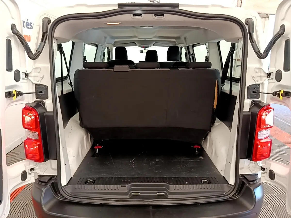 Vue arrière ouverte du Peugeot Traveller blanc 2018, montrant l'espace de chargement et la banquette arrière noire.