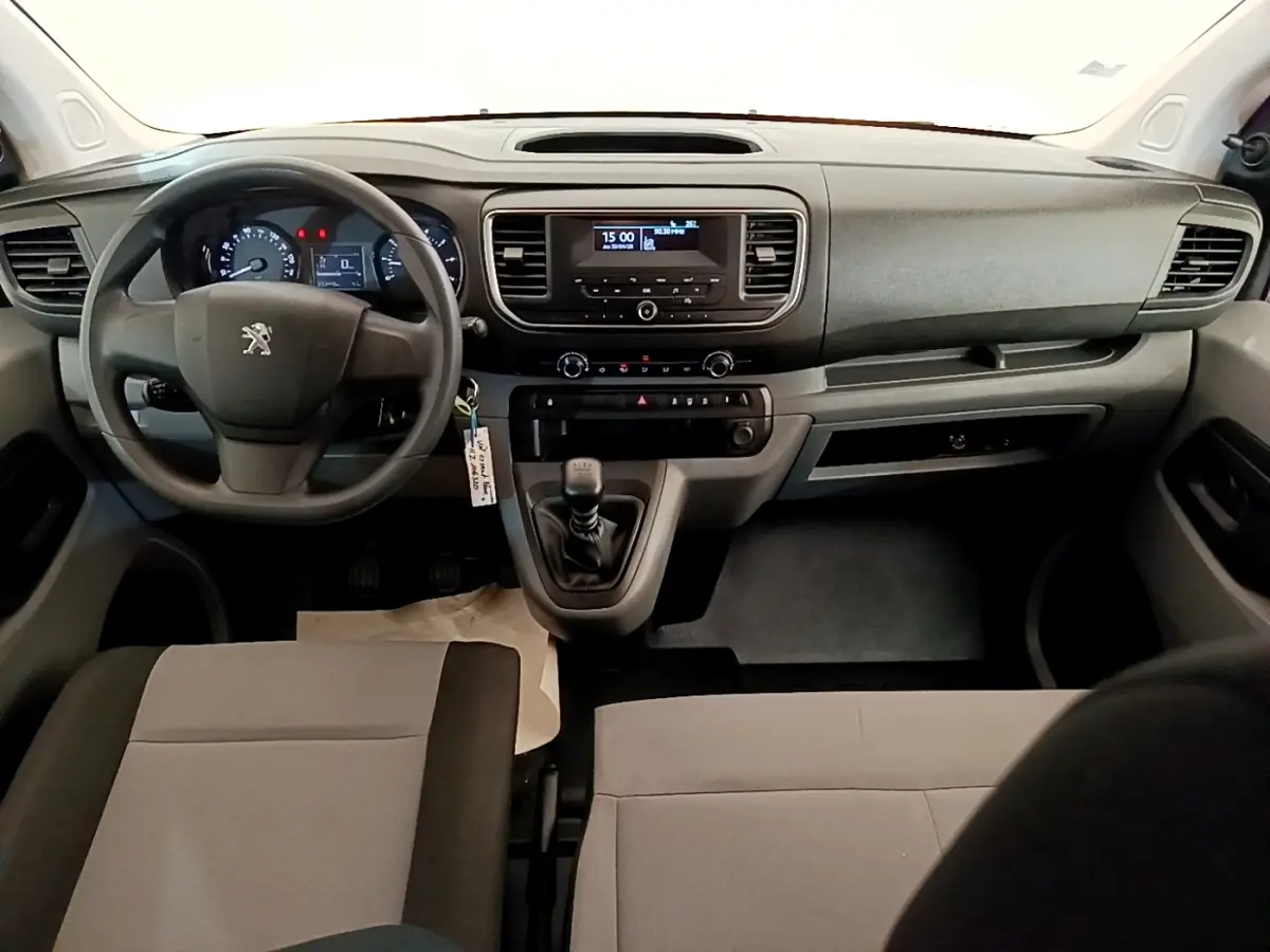 Vue intérieure avant du Peugeot Traveller 2018 avec tableau de bord noir et leviers de vitesses manuelle visibles.