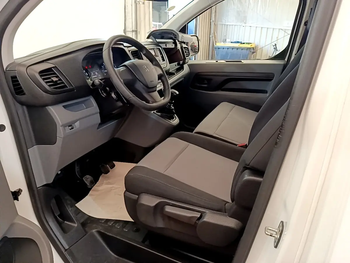 Vue intérieure côté gauche du Peugeot Traveller blanc 2018, montrant le tableau de bord et les sièges avant gris.