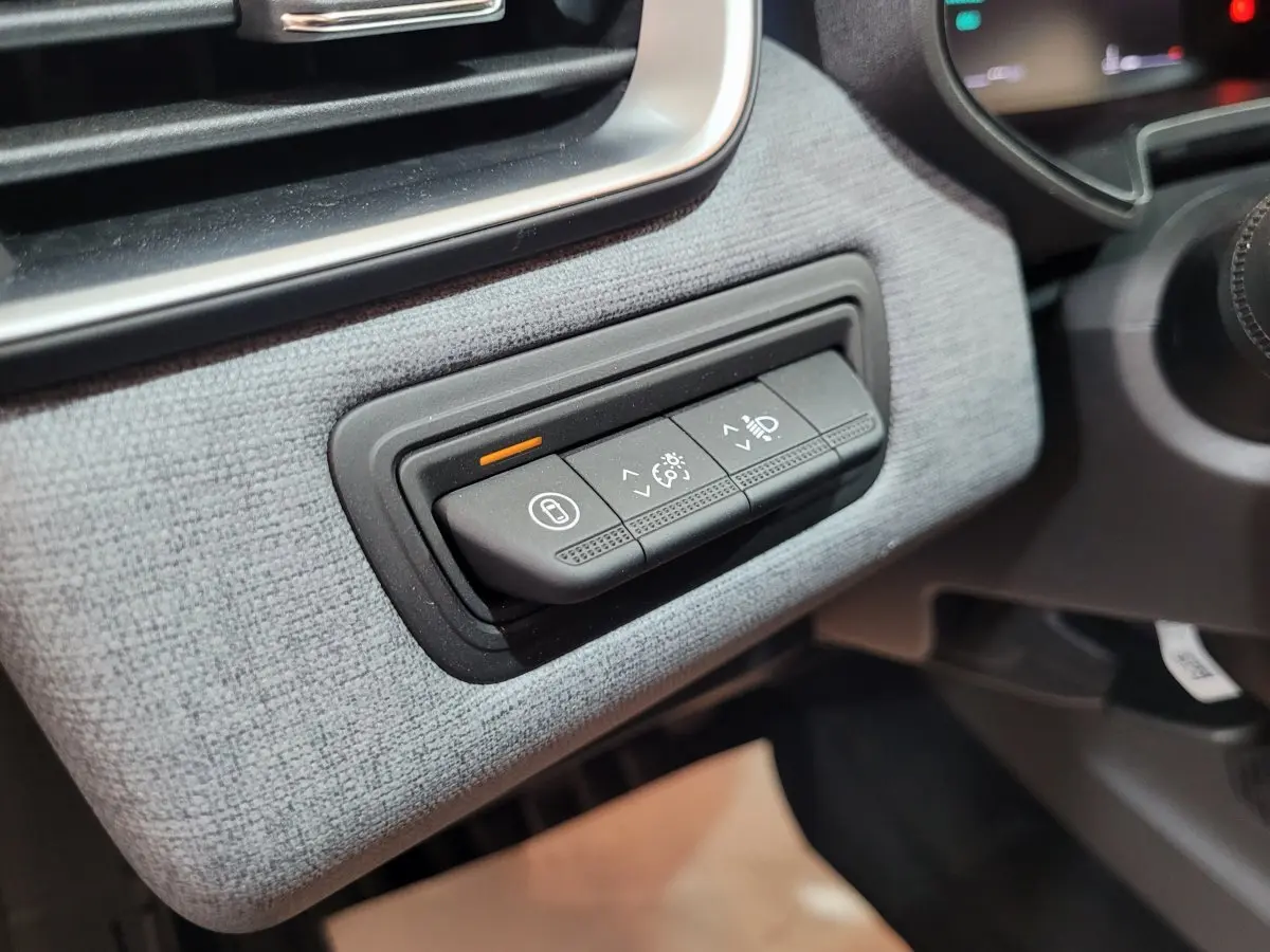 Gros plan sur les commandes d'éclairage et verrouillage, tableau de bord gris clair de la Renault Clio Evolution 2025.