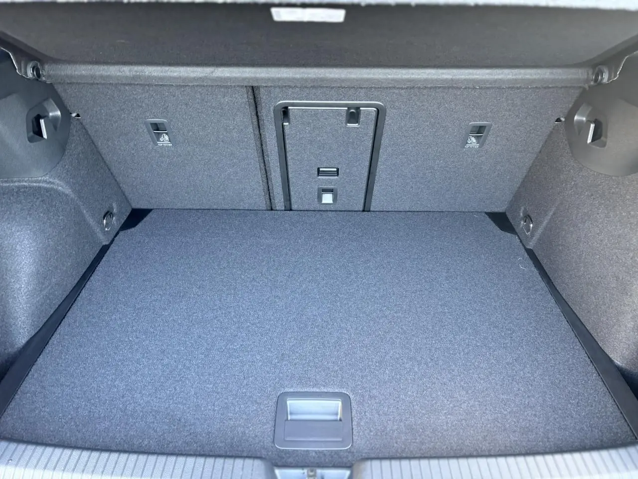 Coffre spacieux de Volkswagen Golf VIII gris Dauphin vu de face, avec revêtement tissu gris uniforme.