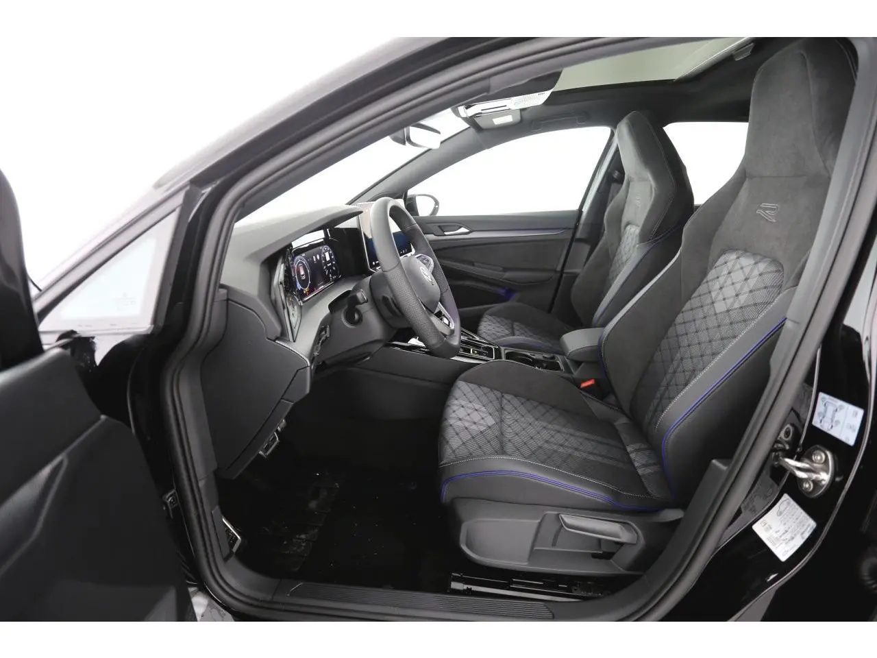 Vue intérieure côté conducteur de la Volkswagen Golf VIII R-Line 2026 avec sièges sport gris et volant cuir multifonctions.