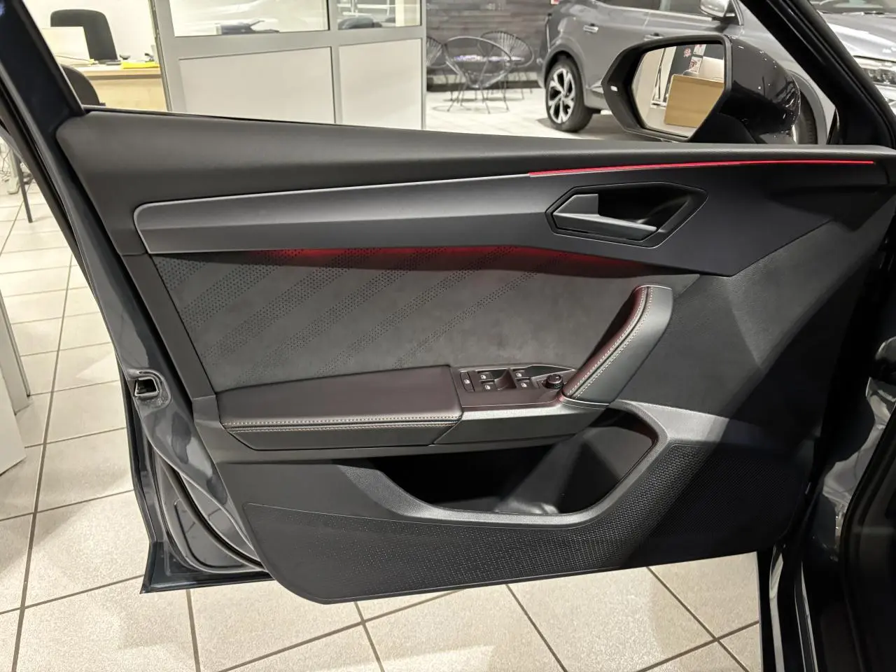 Vue intérieure côté gauche de la porte avant gris graphène avec éclairage d'ambiance cuivré et garniture suédine noire.