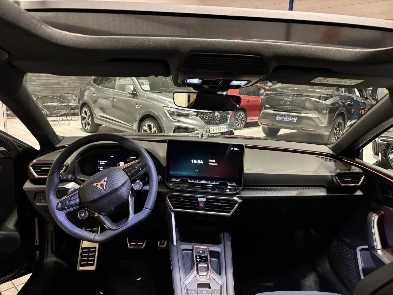 Vue intérieure avant du poste de conduite du CUPRA Leon 2026 avec volant cuir noir et écran tactile central.