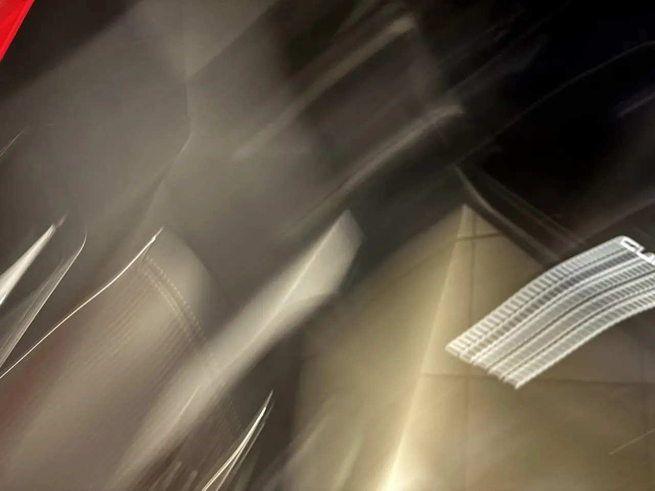 Détail flou du siège avant en suédine noire avec surpiqûres cuivrées et logo CUPRA lumineux projeté au sol.