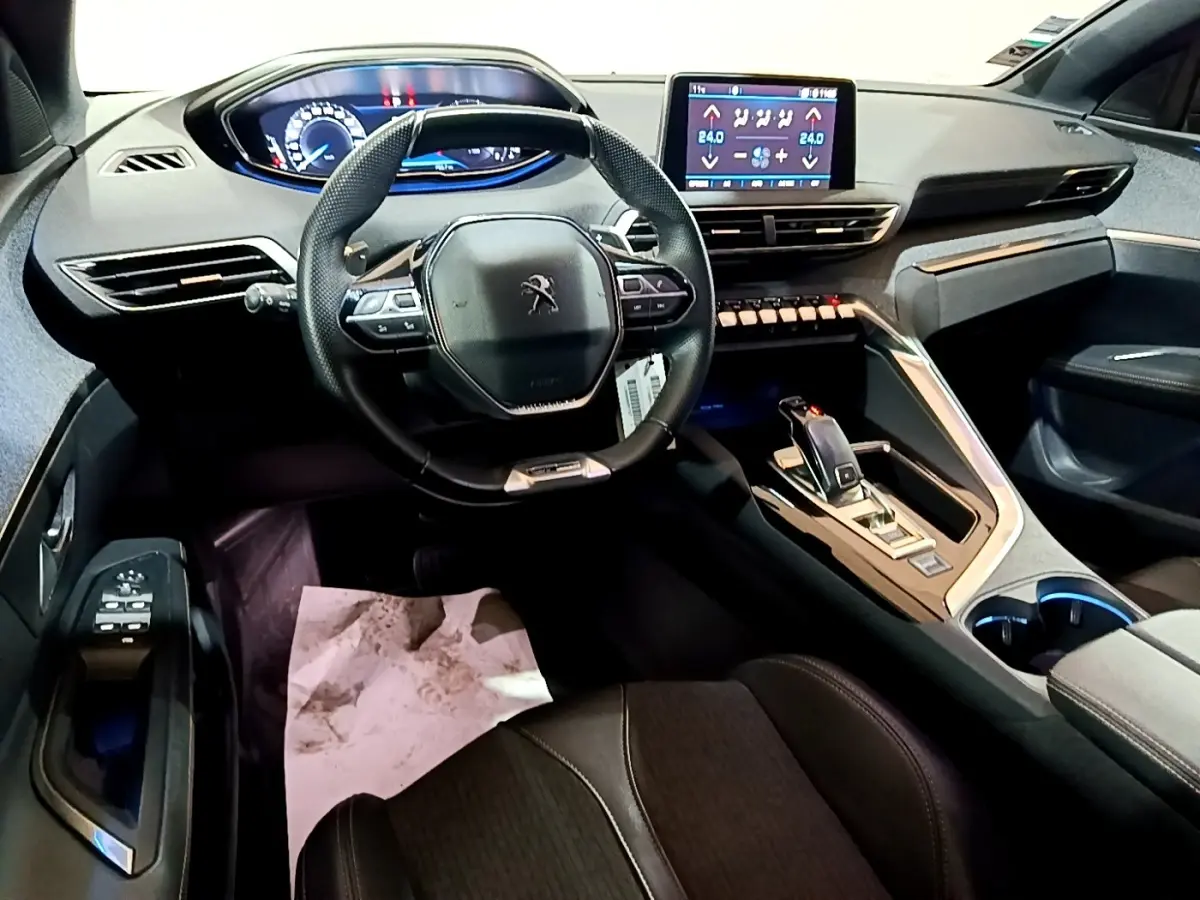 Vue intérieure avant du Peugeot 3008 gris foncé, volant cuir multifonctions et écran tactile central allumé.