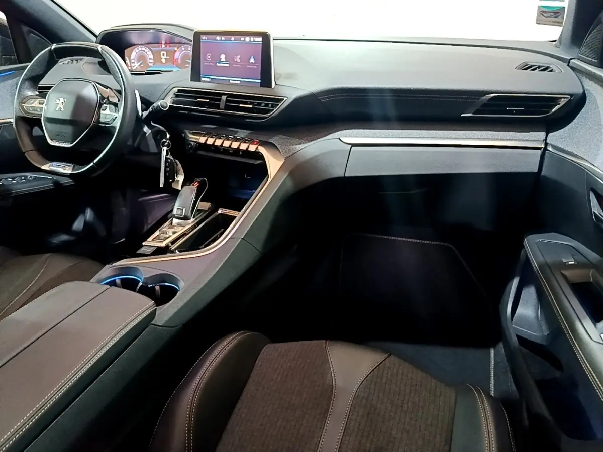 Vue intérieure côté passager du tableau de bord et volant cuir du Peugeot 3008 GT Line gris foncé, avec écran tactile central.